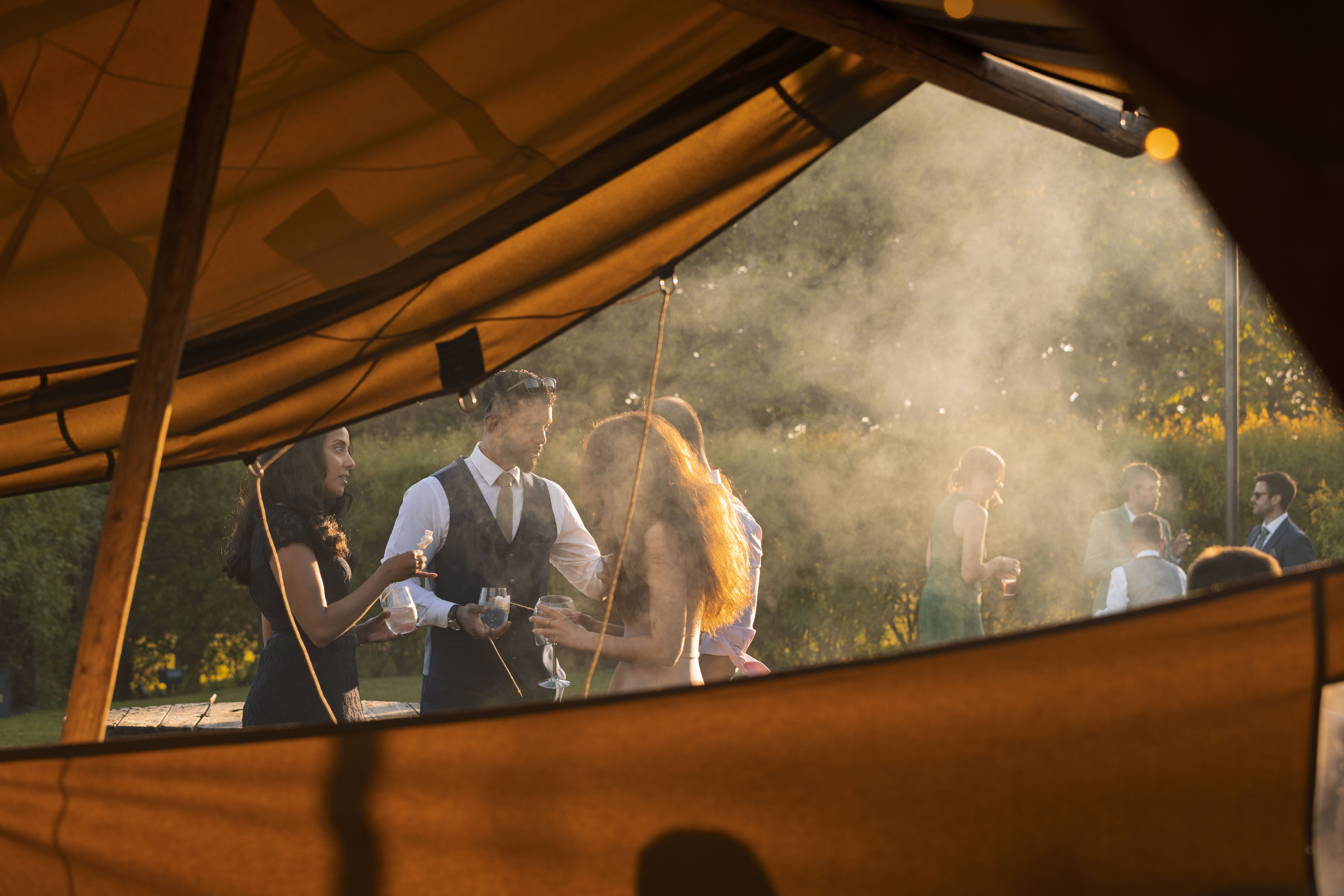 Guests enjoying an outdoor wedding reception at Vallum Weddings pictured from within the open air marquee, with golden sunset lighting, elegant formalwear, and a serene Northumberland countryside backdrop.